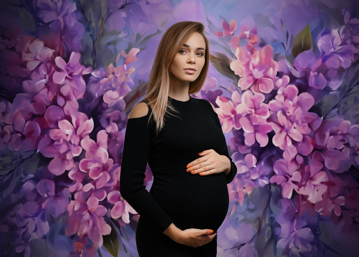 Pregnant mother in black clothes standing in front of purple floral portrait backdrop