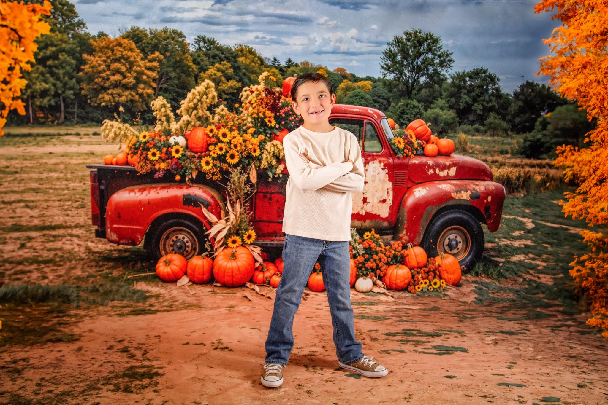 Little boy standing in front of autumn pumpkins red truck backdrop