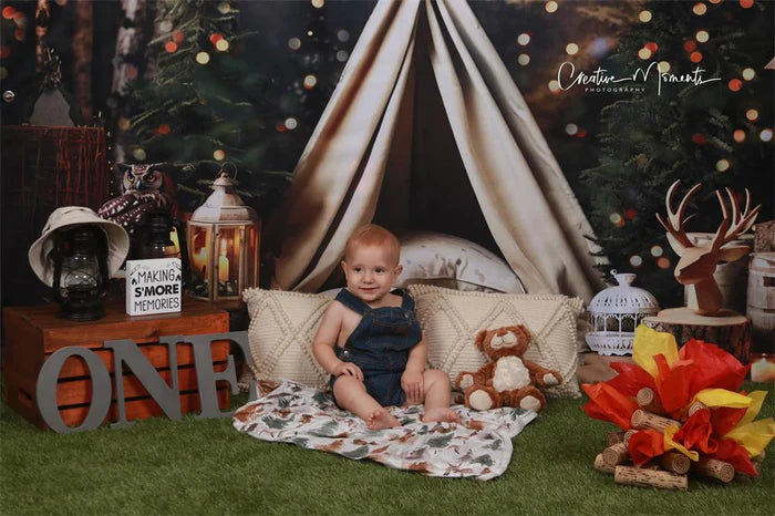 Little kid in denim clothes sitting in front of Christmas tent backdrop