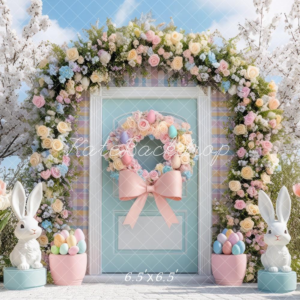 Kate Easter Outdoor Bunny Flower Arch Backdrop with floral wreath, pastel eggs, white rabbits and pink bow on blue door