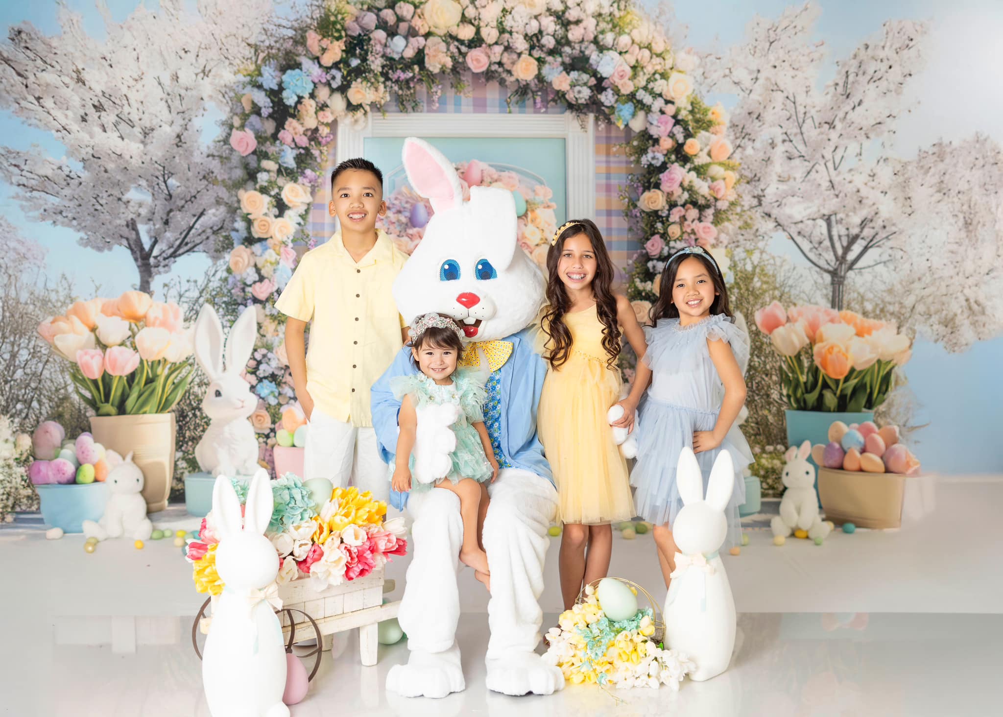 Easter floral arch backdrop with spring decorations, bunny statues, and tulips arranged for holiday photos by Mini MakeBelieve