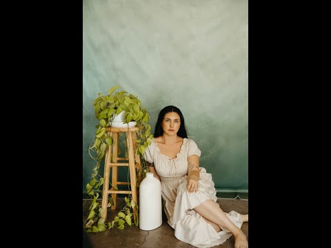 Girl in white dress sitting in front of Cold Darkolivegreen Texture Abstract Backdrop